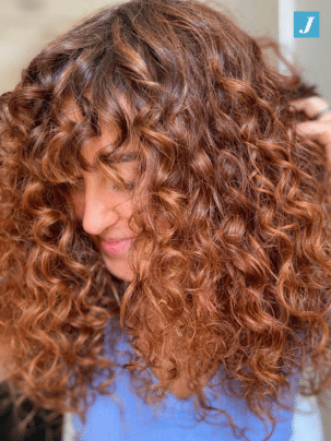 Foto di donna con capelli ricci rosso ramato con frangia con Degradé eseguito